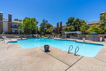 A large swimming pool surrounded by lounge chairs and trees.